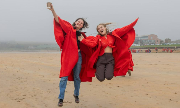 students in red gowns jumping for joy